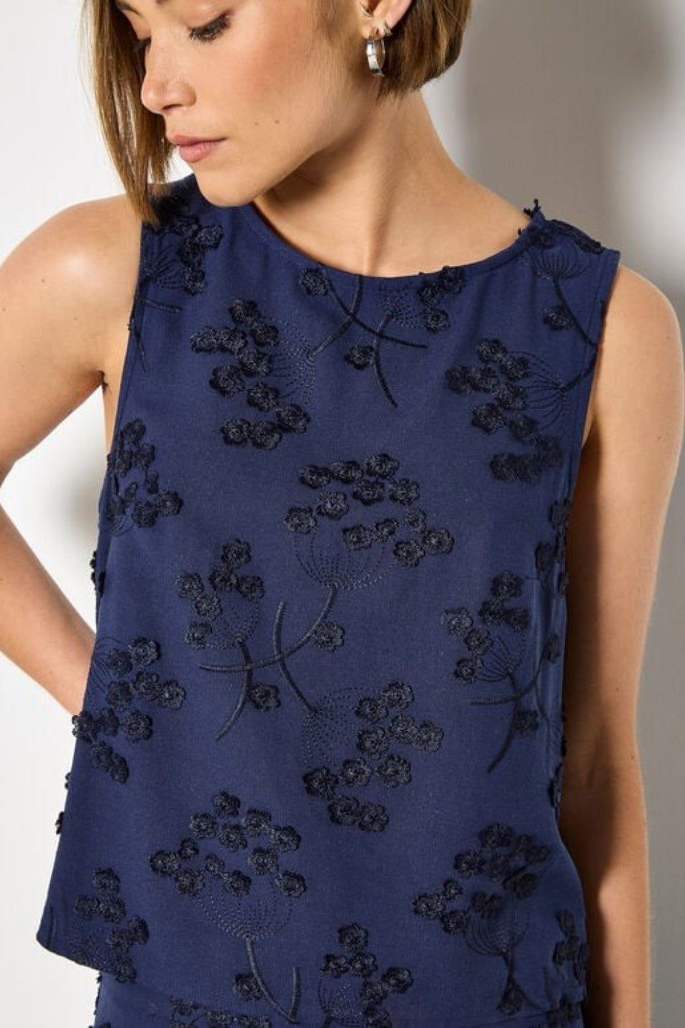 Navy blue sleeveless top with floral embroidery on a plain background