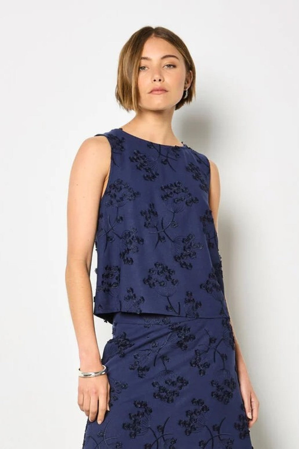 Woman wearing a navy blue floral outfit against a white background
