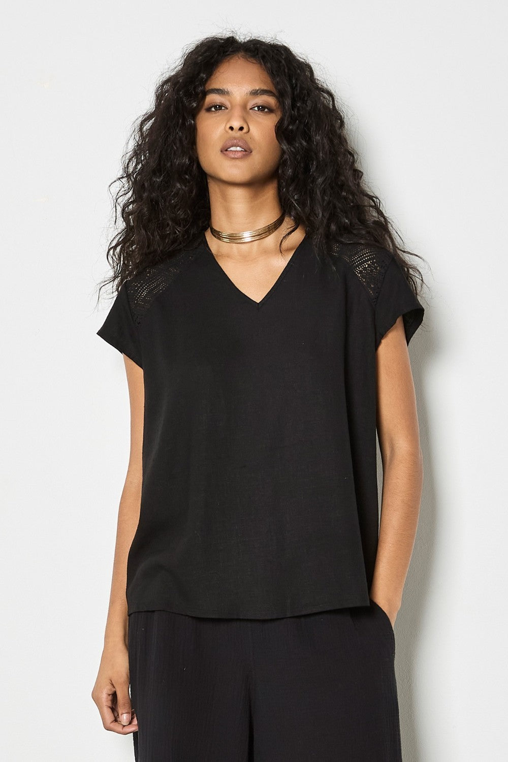 Woman wearing a black top and pants against a white background