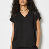 Woman wearing a black top and pants against a white background