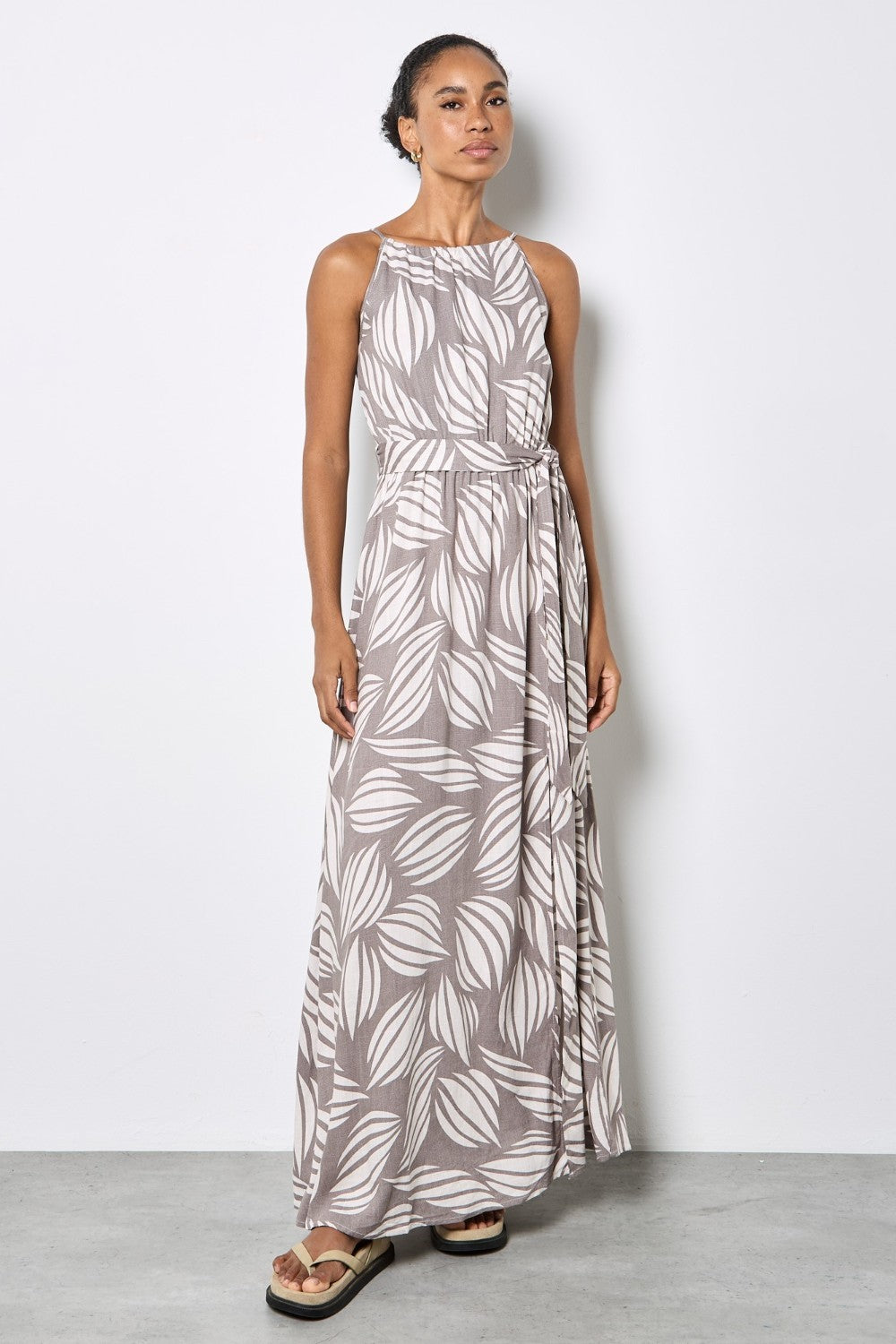 Woman wearing a long leaf-patterned dress against a white background