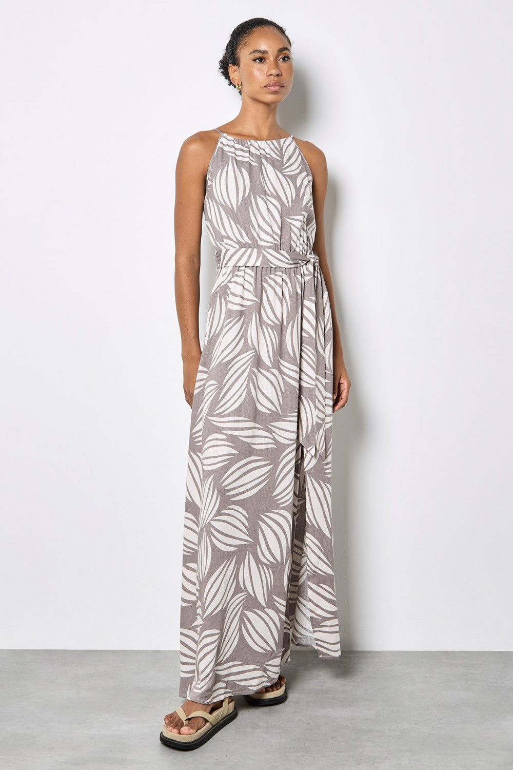 Woman wearing a long leaf-patterned dress against a white background