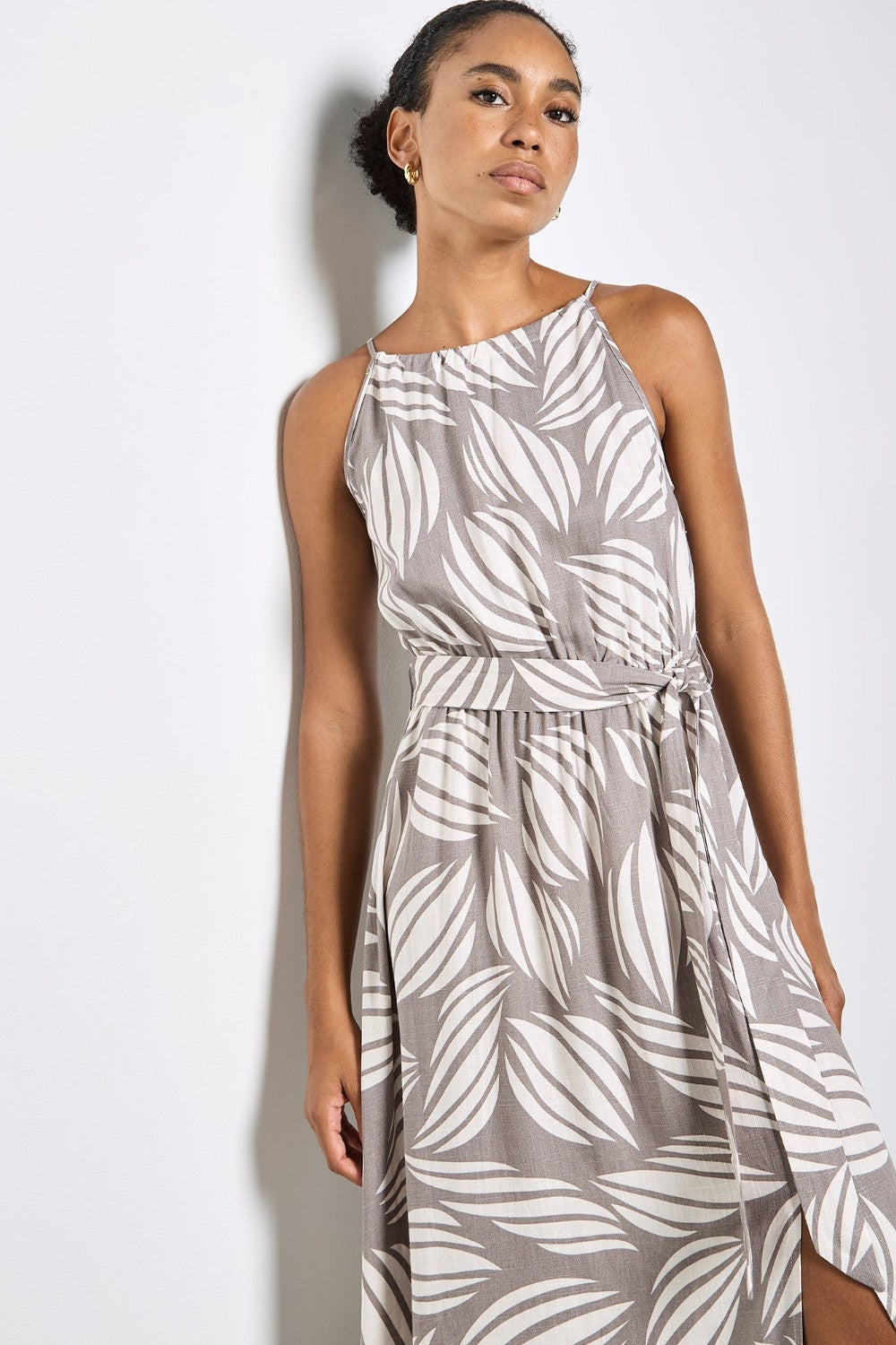 Woman wearing a gray dress with white leaf pattern on a plain background