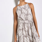 Woman wearing a gray dress with white leaf pattern on a plain background