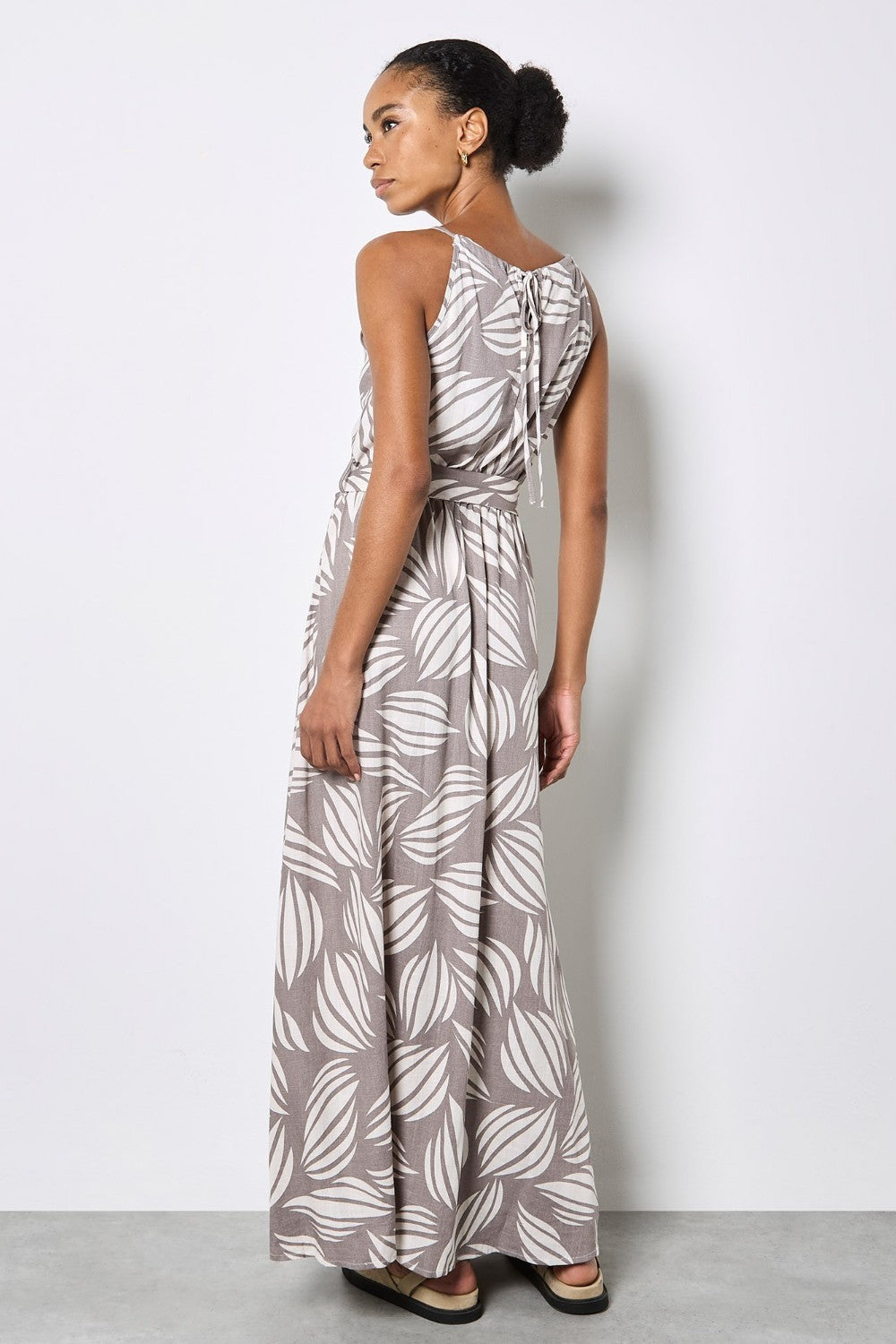 Woman wearing a gray and white leaf-patterned dress against a plain background