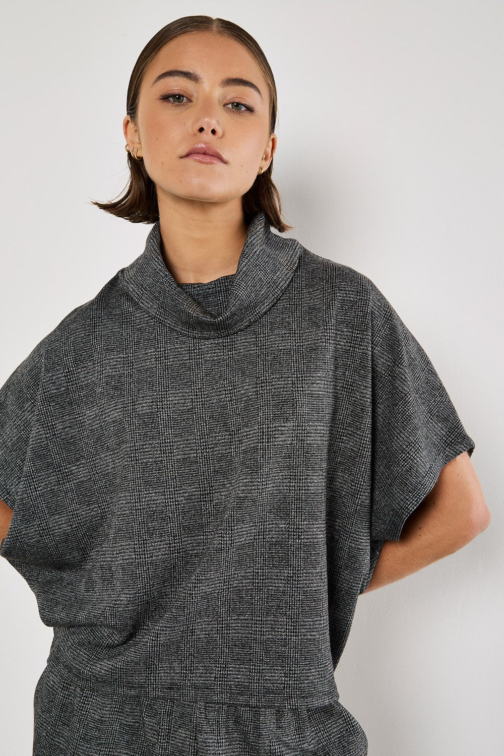 Experience timeless elegance with our Apricot Prince Of Wales Cowl Neck Batwing Top. Made with a classic black and grey check, this top is versatile and perfect for any occasion. Elevate your style with a touch of sophistication.