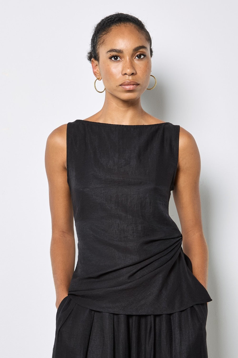 Woman wearing a black sleeveless top with a plain background