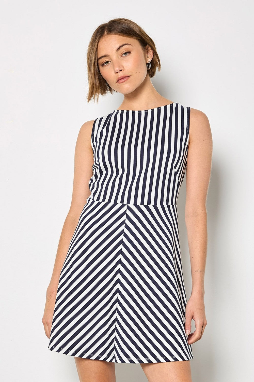 Woman wearing a navy and white striped dress against a plain background