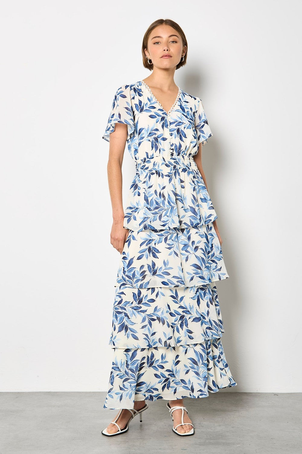 Woman wearing a blue and white floral dress against a white background