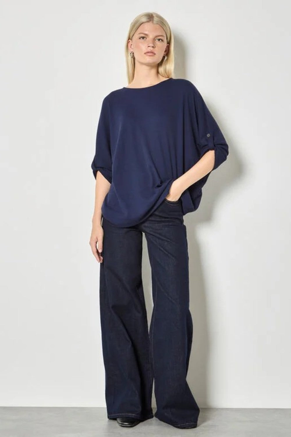 Woman wearing a navy blue outfit with wide-leg pants against a white background