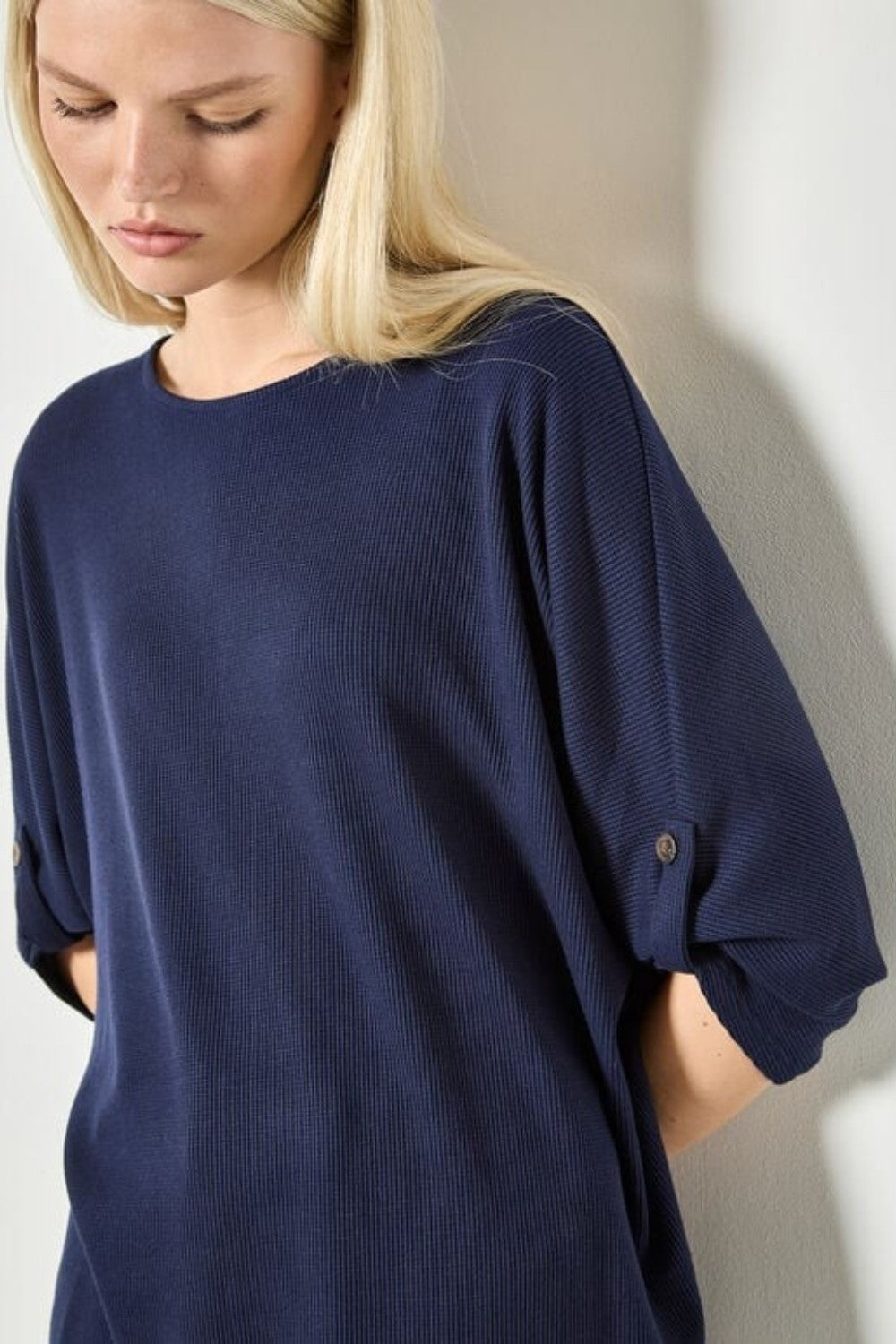 Woman wearing a navy blue oversized shirt against a plain background