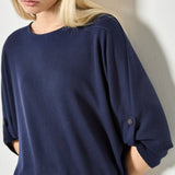 Woman wearing a navy blue oversized shirt against a plain background