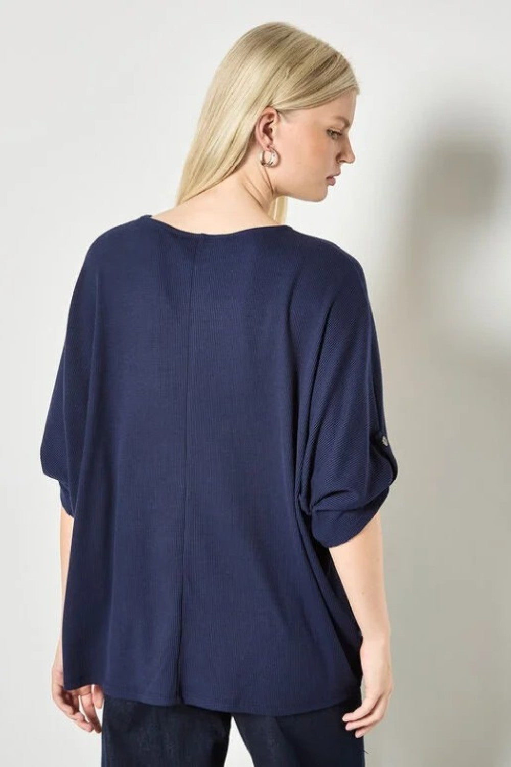 Woman wearing a navy blue top against a plain background