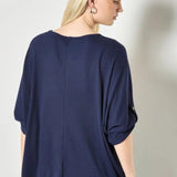 Woman wearing a navy blue top against a plain background