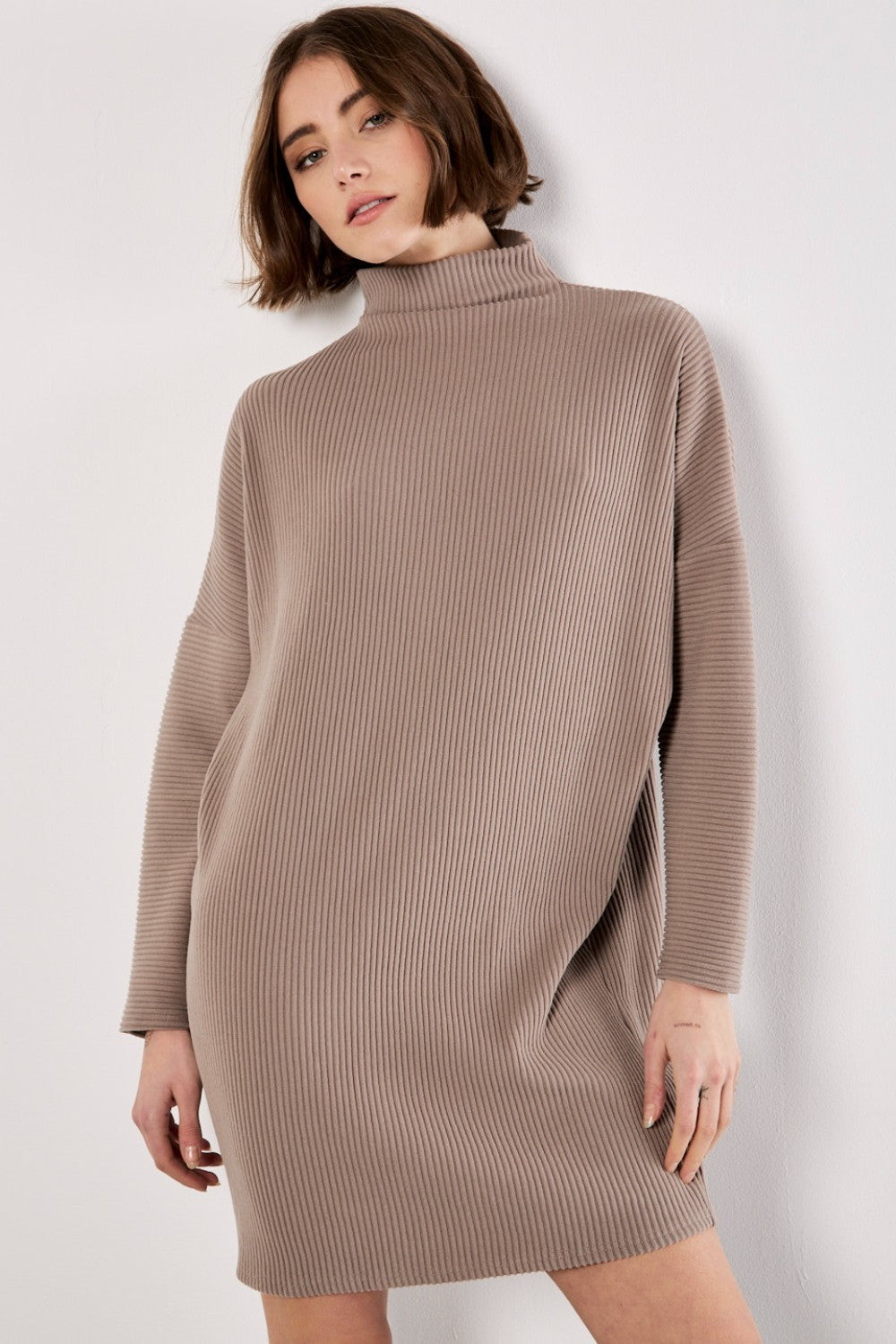 Woman wearing a brown ribbed knit dress against a white background
