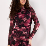 Woman wearing a long-sleeve, patterned dress against a white background