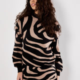 Woman wearing a black and beige zebra pattern dress against a white background