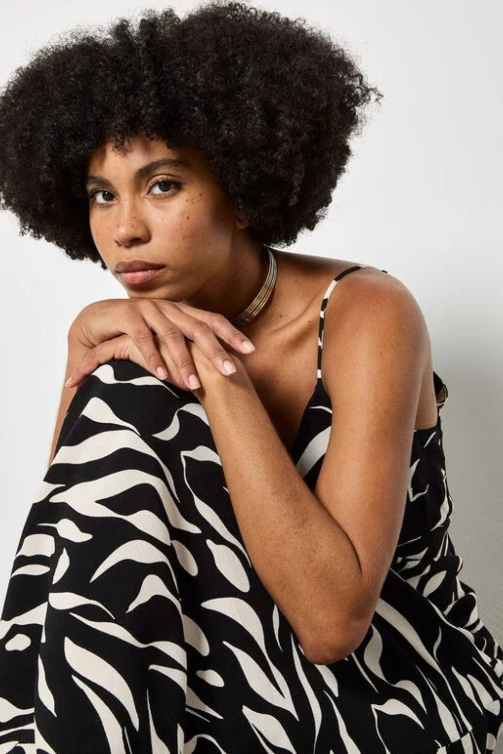 Woman wearing a black and white patterned dress against a plain background