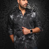 Man wearing a dark patterned shirt against a black textured background