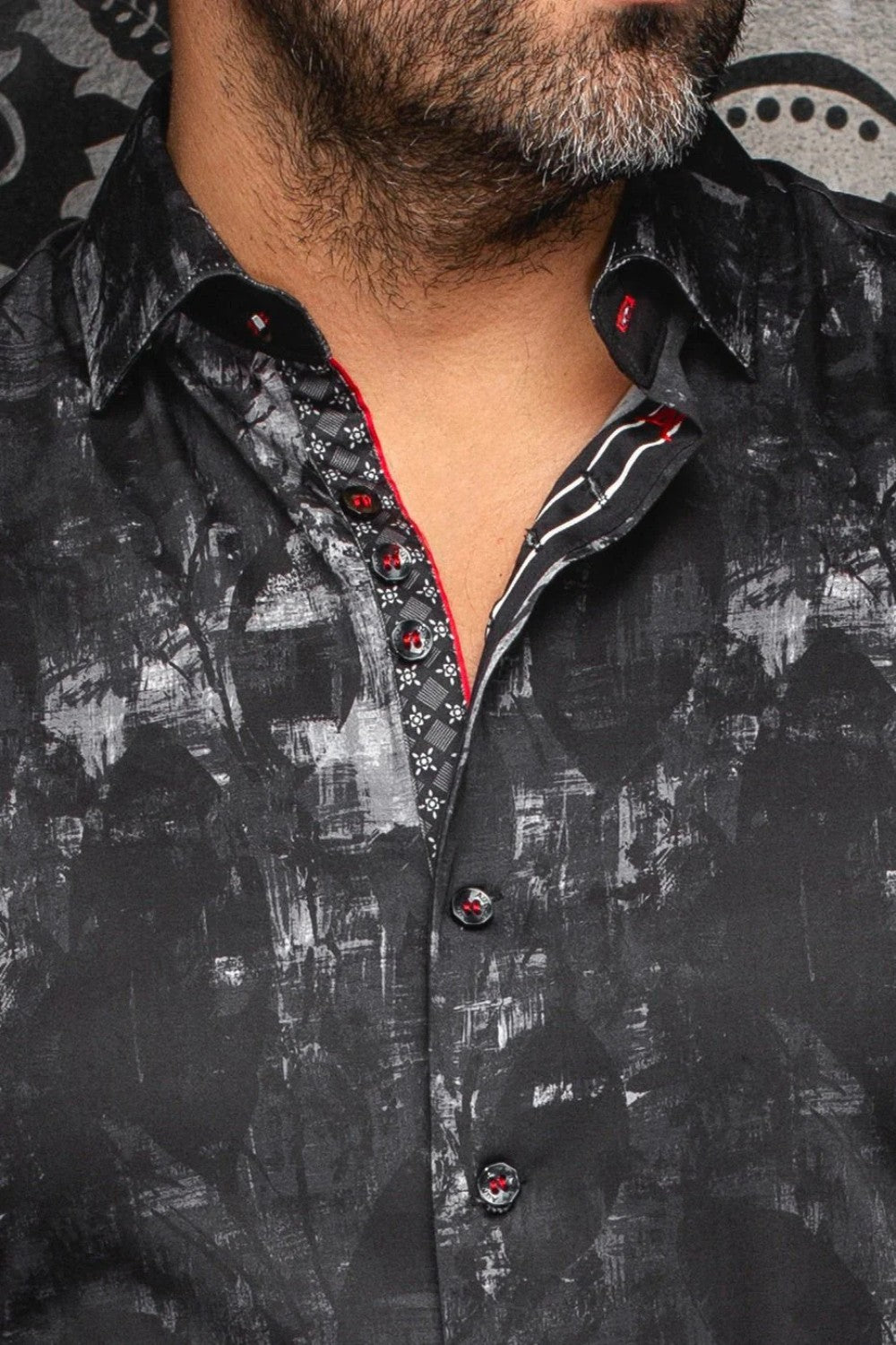 Close-up of a black patterned shirt with red accents worn by a person.