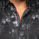 Close-up of a black patterned shirt with red accents worn by a person.