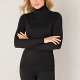 Woman wearing a black turtleneck and pants against a plain background