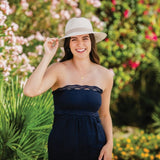 Woman wearing a navy blue strapless romper and light hat in a garden setting with flowers and greenery.