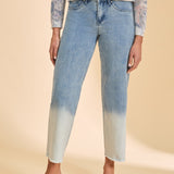 Person wearing a patterned top and blue jeans with a gradient effect on a beige background