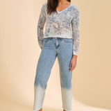 Woman wearing a patterned sweater and blue jeans on a beige background