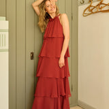 Woman in a red dress standing in a room with wooden flooring and a green wall.