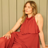 Woman in a red dress sitting on a wooden floor against a green paneled wall.