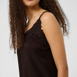 Woman wearing a brown lace-trimmed top against a white background
