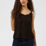 Woman wearing a brown sleeveless top with lace details and blue jeans on a white background