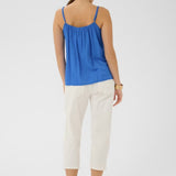 Woman wearing a blue top and white pants on a light gray background