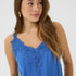 Woman wearing a blue sleeveless top with lace detailing on a white background