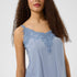 Woman wearing a light blue sleeveless top with lace details on a white background