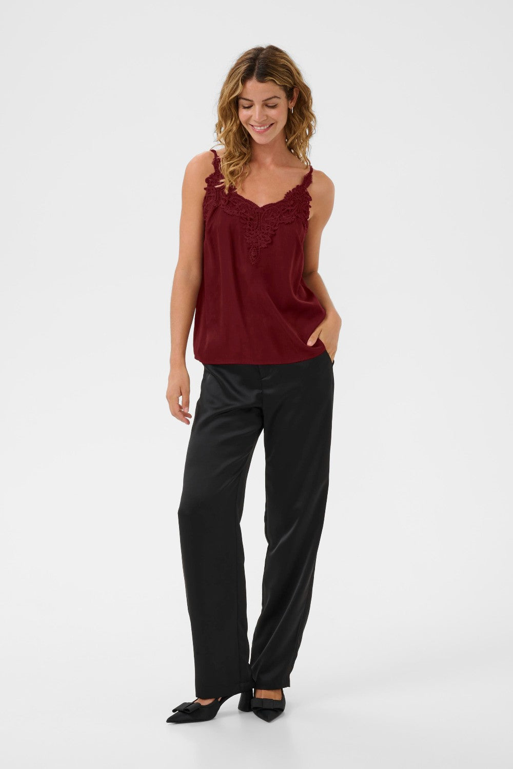 Woman wearing a burgundy top and black pants on a white background