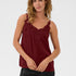 Woman wearing a burgundy sleeveless top with lace details on a white background
