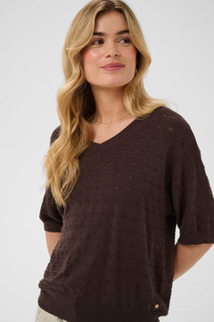 Woman wearing a brown sweater against a white background