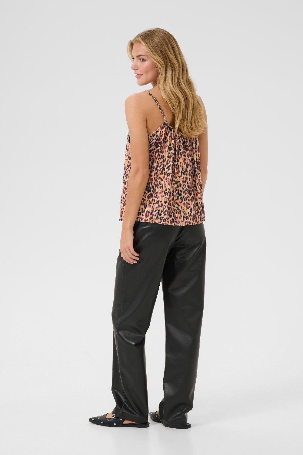 Woman wearing a leopard print top and black pants on a white background