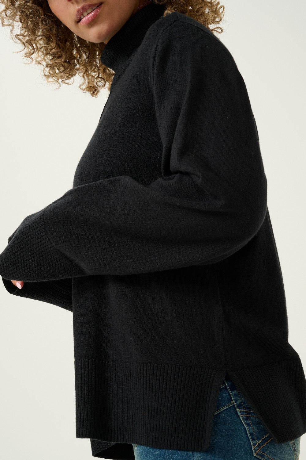 Person wearing a black sweater with a plain background