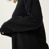Person wearing a black sweater with a plain background
