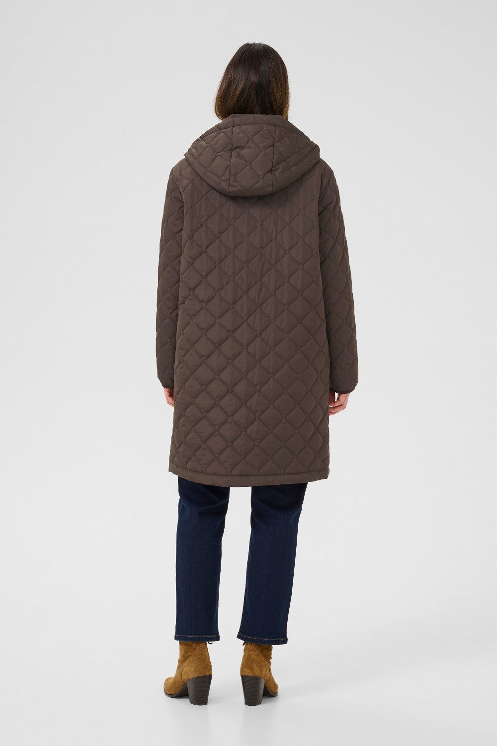 Person wearing a brown quilted coat on a white background