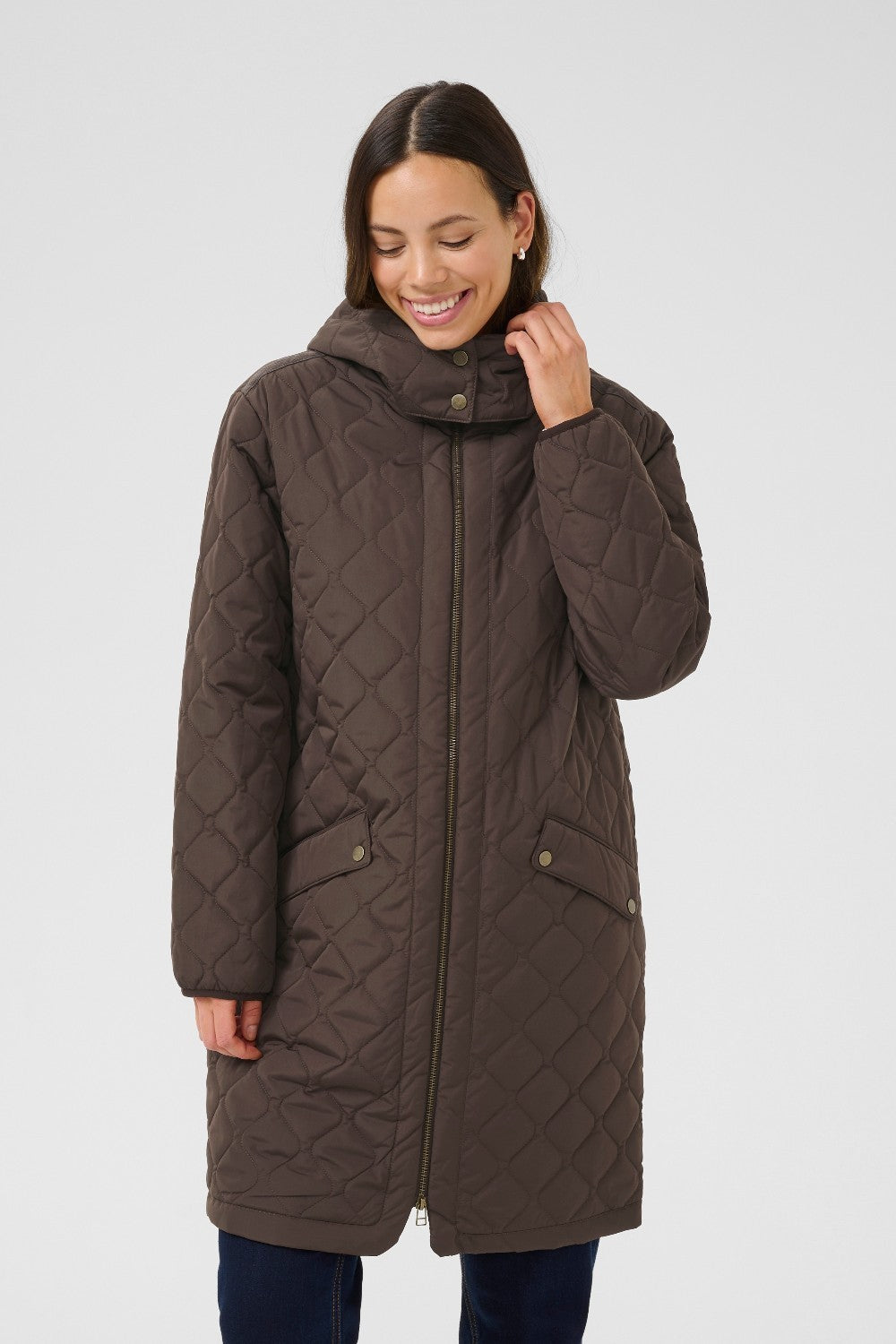 Woman wearing a brown quilted coat on a white background