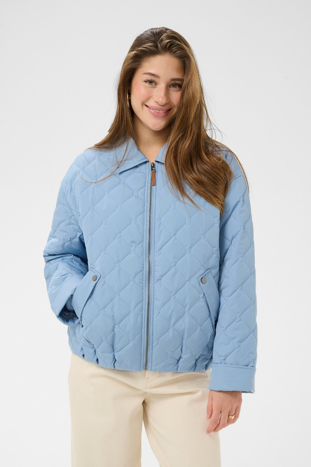 Woman wearing a light blue quilted jacket on a white background