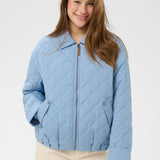 Woman wearing a light blue quilted jacket on a white background