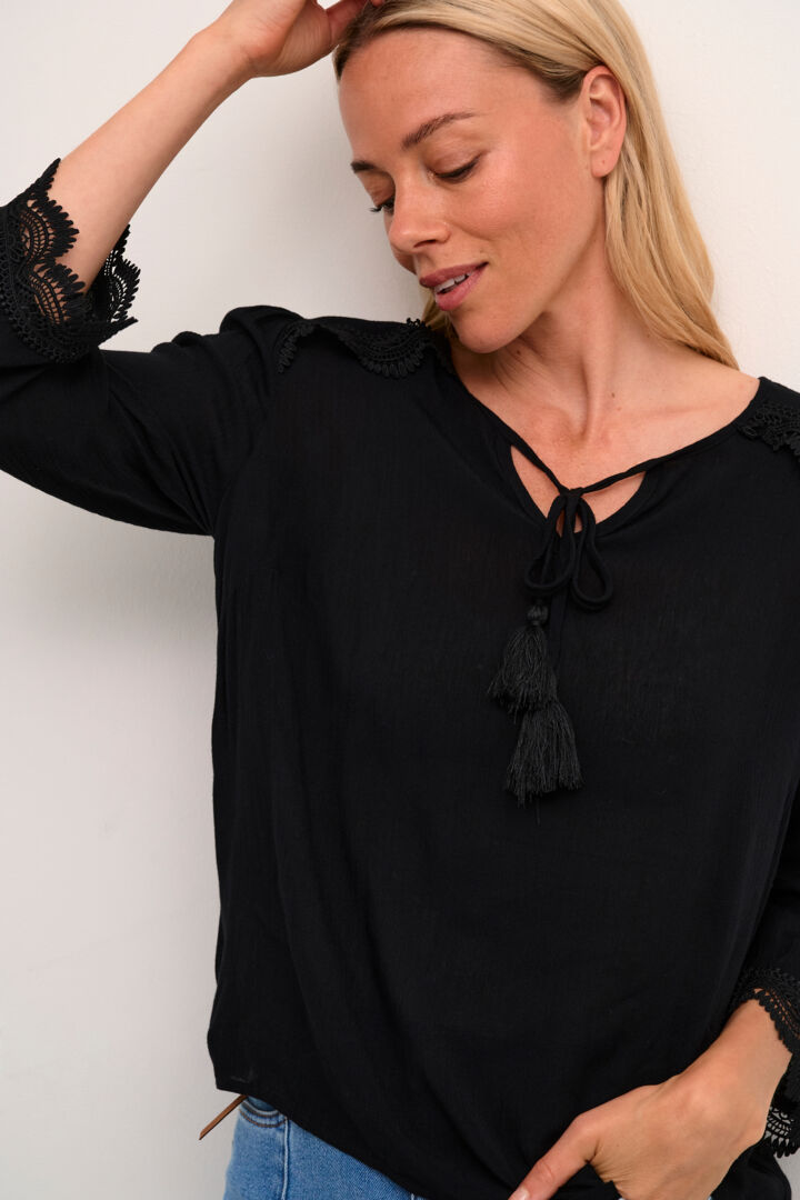 The Cream Bea 3/4 Sleeve Lace Blouse features a sleek black colour and a charming front tie with tassels. Elevate any outfit with this versatile piece, perfect for adding a touch of sophistication to your wardrobe.