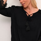 The Cream Bea 3/4 Sleeve Lace Blouse features a sleek black colour and a charming front tie with tassels. Elevate any outfit with this versatile piece, perfect for adding a touch of sophistication to your wardrobe.