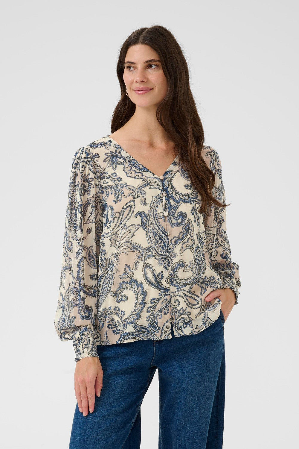 Woman wearing a patterned blouse and blue jeans on a white background