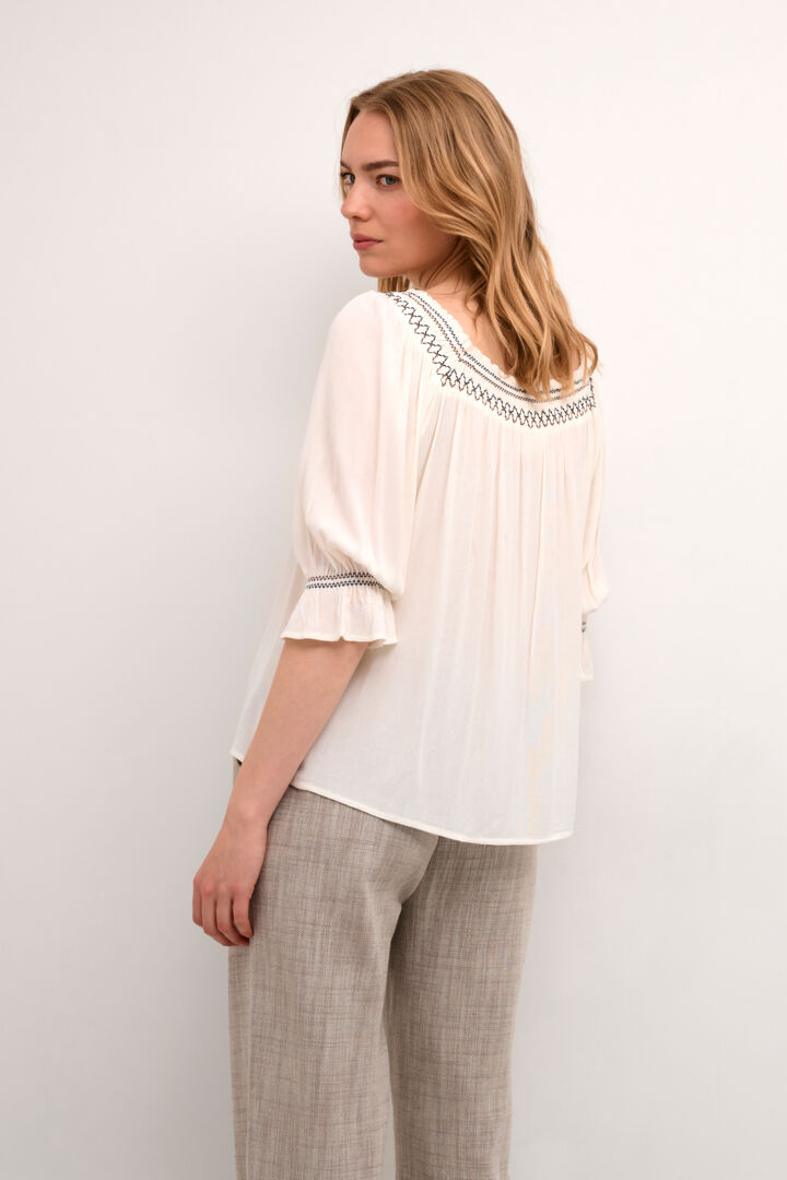 This Cream Bea Smock Blouse features a beautiful off-white colour with intricate black and brown embroidery on the neck and sleeves. With a delicate smocked design, this blouse exudes elegance and style. Perfect for any occasion, it is a must-have addition to any wardrobe.